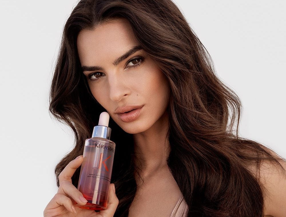 Model with long brunette hair holding Kérastase Genesis Serum Anti-Chute Fortifiant